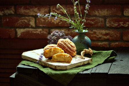 Appetizing swirl buns on a board with green cloth underneath next to a vase of wildflowers on a wooden table against the red brick wall. still life. baked at home. Food Magazine Layoutの写真素材