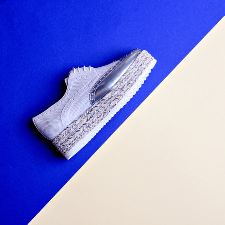 Trendy women's gray-silver platform oxford shoe isolated on two-color background with pointing on copy space. Summer - autumn shoe sale campaign. Creative design for shoe store advertising poster.の写真素材