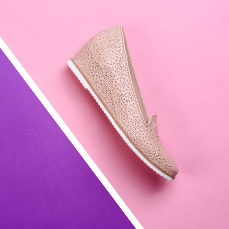 Stylish beige women's hidden wedge moccasin with a perforated pattern and white sole isolated on a creative graphic pink-purple-white background. Mock-up for a shoe store advertising design. Retail.の写真素材