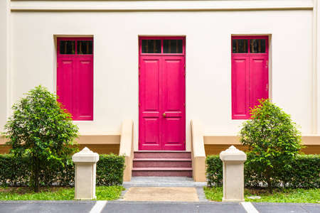 Red Door , red window on Cream Wall on red staircase with small tree backgroundの写真素材