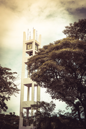 Clock tower and big tree on blue sky at bangkok thailand