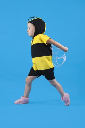 Small girl is dressed at bee costume on blue backgroundの写真素材