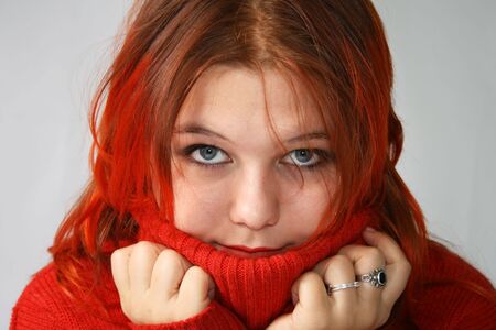 Young girl hides into the collar of the red sweaterの写真素材