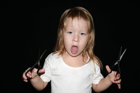 Little girl with scissors. Black background.の写真素材