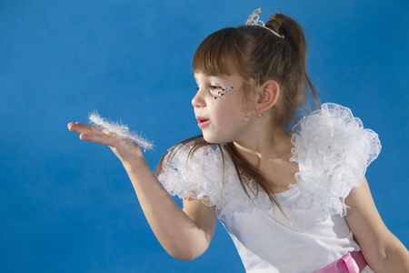 Little girl blows on a snowflake. A blue backgroundの写真素材