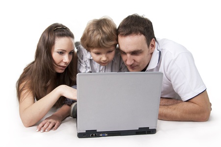 Young family lying on a floor with the computer on white isolationの写真素材