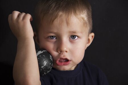 Portrait of the serious boy on a black backgroundの写真素材