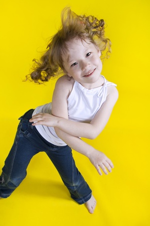 Cheerful girl dances on a yellow backgroundの写真素材