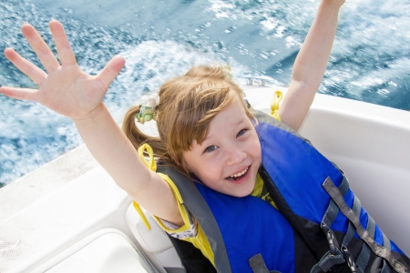 Two kids sitting in the bow of a boat with there life jackets having funの写真素材