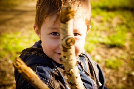 The boy plays with sticks on the street in the autumn afternoonの写真素材
