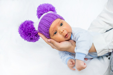 The baby in a lilac knitted hat with big pomponsの写真素材