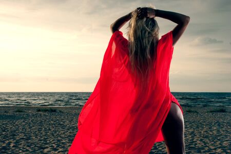 Young girl in red dress on the seaの写真素材