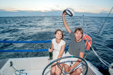 Happy young couple drinking champagne on yachtの写真素材