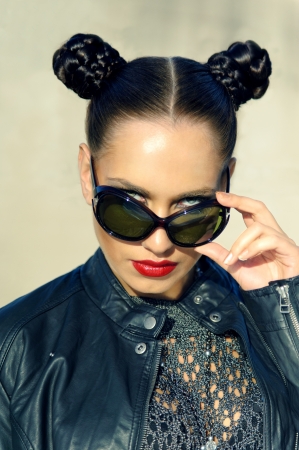 girl with pigtails peeking from behind sunglassesの写真素材