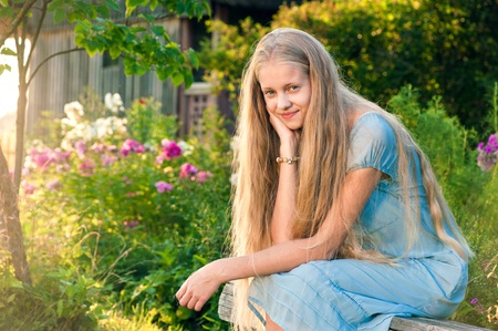 Beautiful young girl with long blond hair in blue dress in the countrysideの写真素材