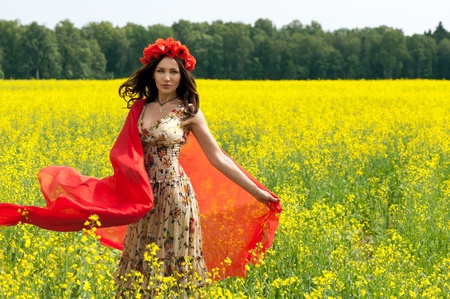 Beautiful young brunette girl wearing flower chaplet in summer filedの写真素材