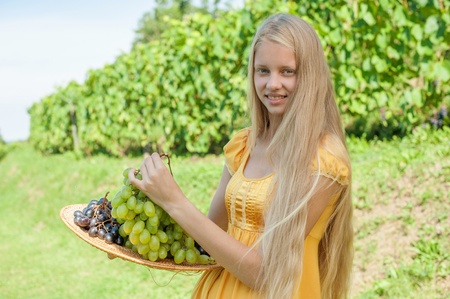 Portrait of a beautiful young blonde holding bowl of grapesの写真素材