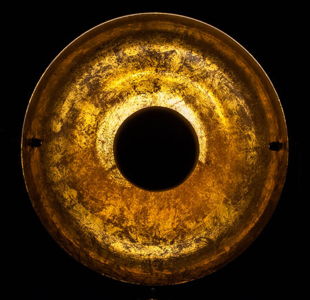 Old round gold object on black backgroundの写真素材