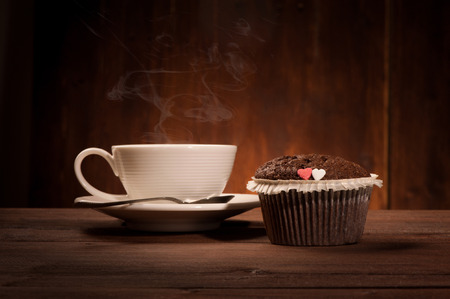 Delicious tasty cupcake and coffe cup on wooden tableの写真素材