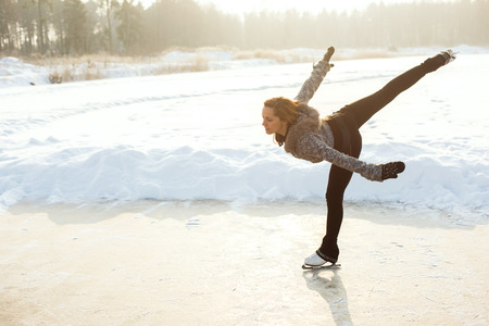 young Figure skating woman at the frozen lake in the winter