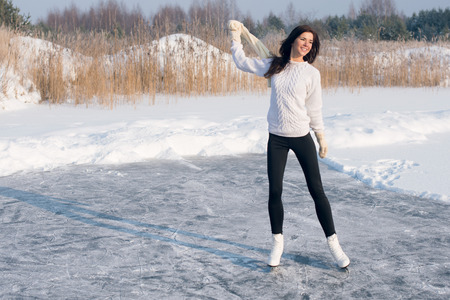 young Figure skating woman at the frozen lake in the winterの写真素材