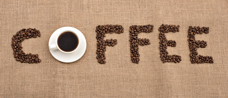 word coffee of coffee beans and cup of black coffee on bagging backgroundの写真素材