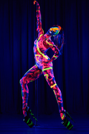 Female pole dancer in bright neon colours under ultraviolet (UV) light on backgroundの写真素材