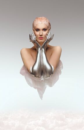 Fantasy portrait of beauty cyber woman from the future with clay hairstyle and silver hands above cloudsの写真素材