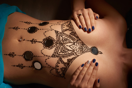 Eastern beautiful brunette woman with mehendi on her stomachの写真素材