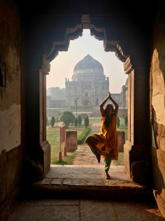 Caucasian female doing yoga in Bada Gumbad Complex at early morning in Lodi Garden Monuments, Delhi, Indiaの写真素材