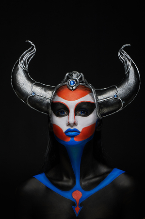 Mystery portrait of female faun with blue eyes, body art and silver snakes on black hornsの写真素材