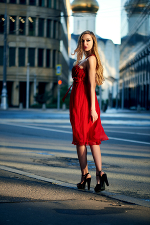 Beautiful blonde lady in red dress on White Square office center in Moscow, Russiaの写真素材