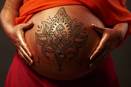 Pregnant woman with golden body art and mandala in buddha look の写真素材