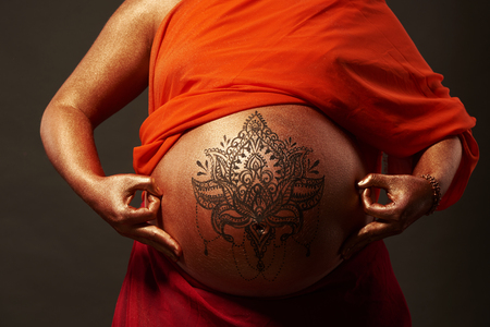 Pregnant woman with golden body art and mandala in buddha look の写真素材