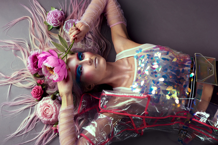 Gorgeous woman in biofuture pompadour style. Female in fashion transparent raincoat with splendid make up and hairstyleの写真素材