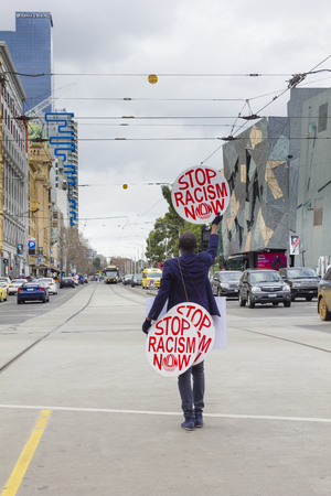 Melbourne, Australia - July 25, 2015: View of an unidentified protester holding stop racism now placards outside the Flinders Street Station in Melbourne.のeditorial素材