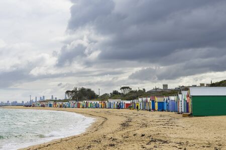 Melbourne, Australia - August 11, 2015: Colourful bathing houses at Dendy Street Beach, Brighton in Melbourne on a cloudy day in winter with Melbourne skyline in the distance.のeditorial素材