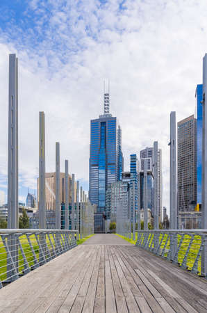 Footbridge with cityscape in the background on a cloudy dayの写真素材