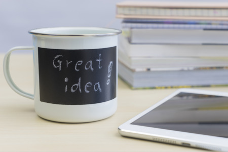 Great idea words on coffee mug with tablet and stack of books on tableの写真素材