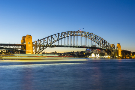 Sydney, Australia - June 25, 2016: View of Sydney Harbour Bridge at night with ship in motion blur and Luna Park and modern buildings in a distance at twilight.のeditorial素材