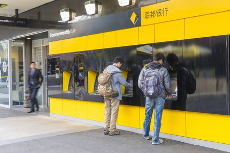 Melbourne, Australia - September 4, 2015: View of two persons using the ATMs outside the Commonwealth Bank in Melbourne while a man walking out of the bank.のeditorial素材