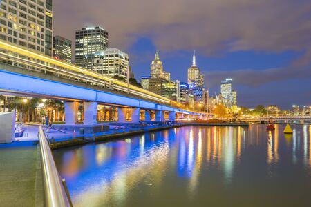 Melbourne, Australia - September 18, 2015: Multiple exposure image of skyscrapers and light trail of trains in downtown Melbourne, Australia at twilight.のeditorial素材