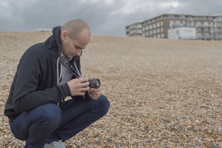 Young bald man taking photos of the sea and wavesの写真素材