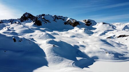 Aerial view of the Alps mountains in France. Mountain tops covered in snow. Alpine ski facilities...