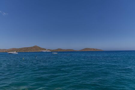 Summer sea view from coast with white yaht and mountains in background, Greeceの写真素材