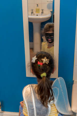 A young girl from poor deprived family is entertaining herself by face paintingの写真素材