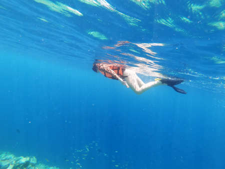 Silhouette of scuba diver and sunlight in the blue waterの写真素材