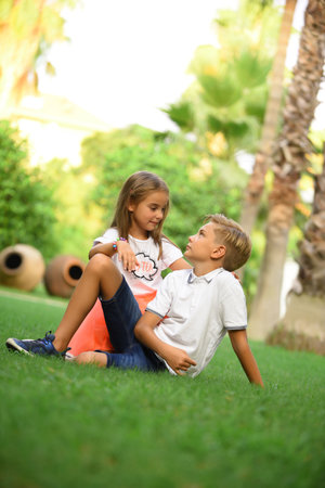 Brother and sister run, play and have fun on the grass in the park on a summer day during sunset. Happy childhood.の写真素材