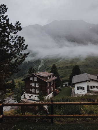 House on top of a mountain with clouds and sunset on the backgroundの写真素材