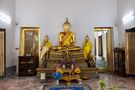 A Serene Golden Buddha Statue is beautifully placed within a Tranquil Temple Settingの写真素材
